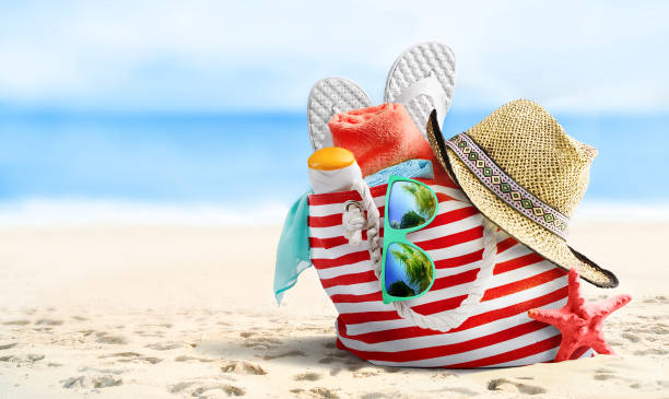 Summer vacations concept background. Beach bag, straw hat, flip flops, sunglasses and starfish on sandy beach and azure sea on background.
